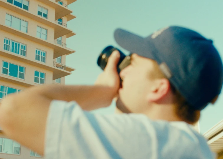 a man with a hat and sunglasses looking through binoculars