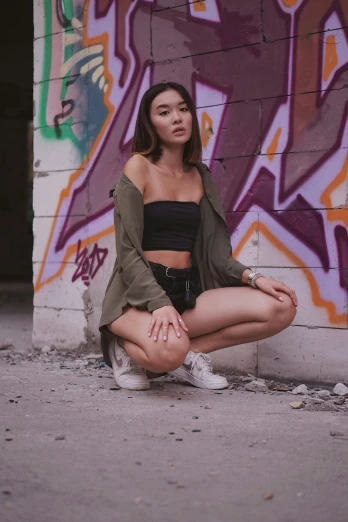 a girl with short hair sitting on the ground next to a wall