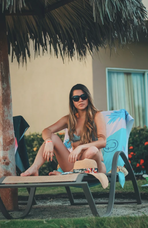 a woman sits on her beach towel on a chaise