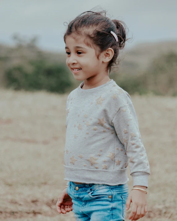 a  with a ponytail in her hair smiling at the camera