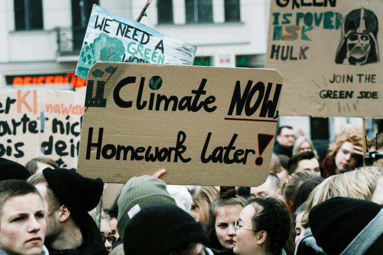 a group of people standing around each other in the street holding signs