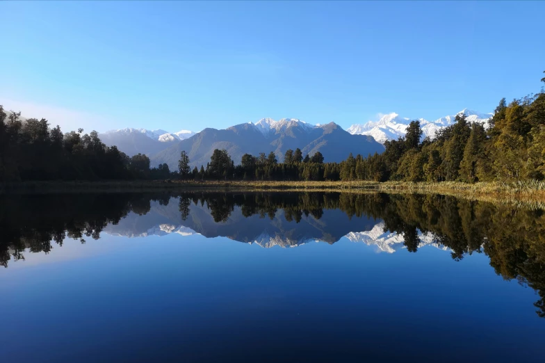 a lake surrounded by forest covered mountains near the mountains