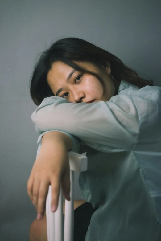 a woman is leaning against a chair with her arm on the back of the chair