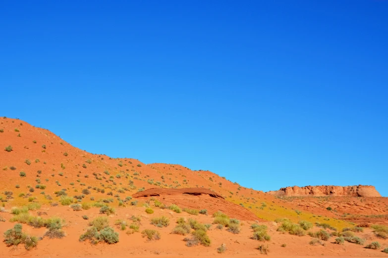 a mountain with green shrubs on top and blue sky above