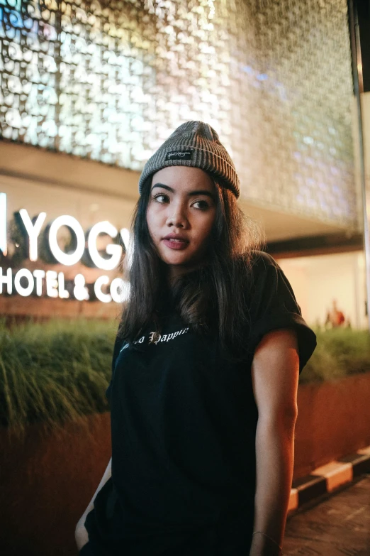 a beautiful young woman wearing a hat next to a wall