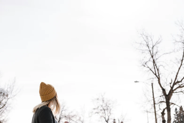 a young woman in a beanie looking at the sky