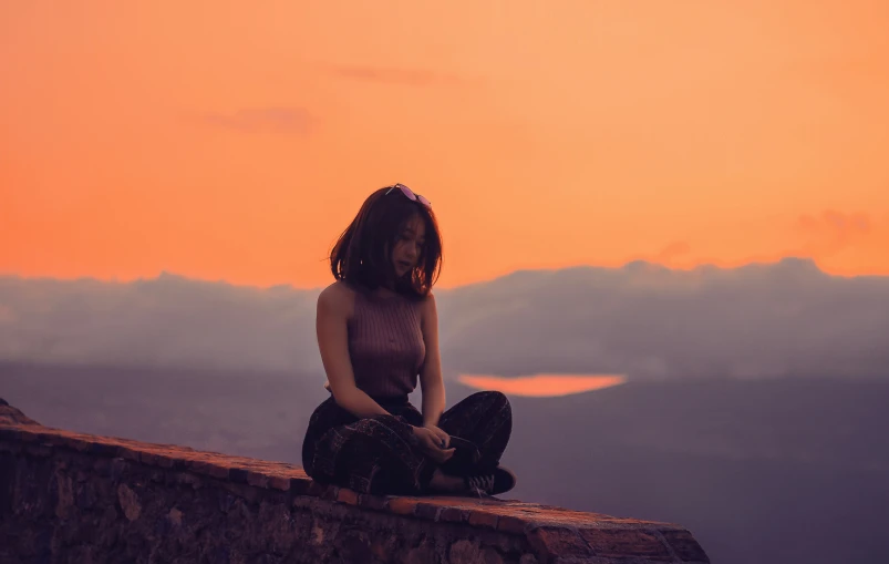 a person that is sitting on the edge of a wall