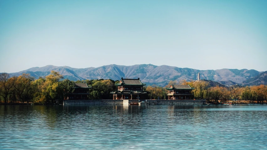 a view from across a river shows a few pavilions and a mountain range in the background