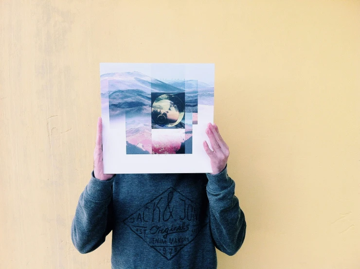 a person holding a white polaroid while covering their face with both hands