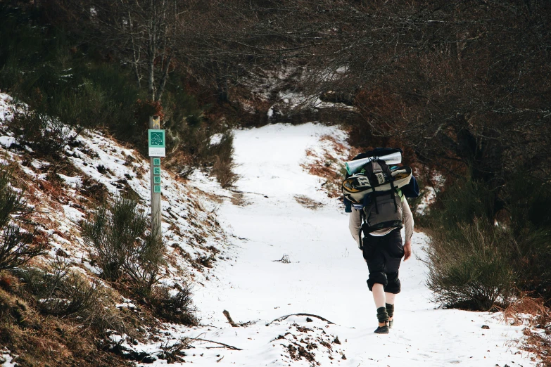 a man with a backpack on walking up a snow covered path