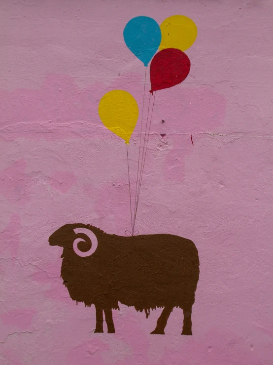 a goat with balloons attached to it in front of a pink background