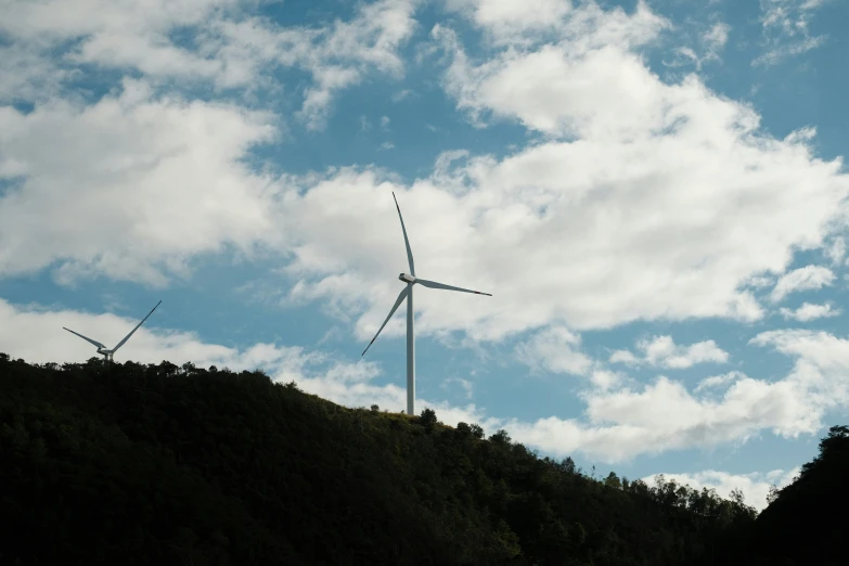 three wind turbines are on the side of a hillside