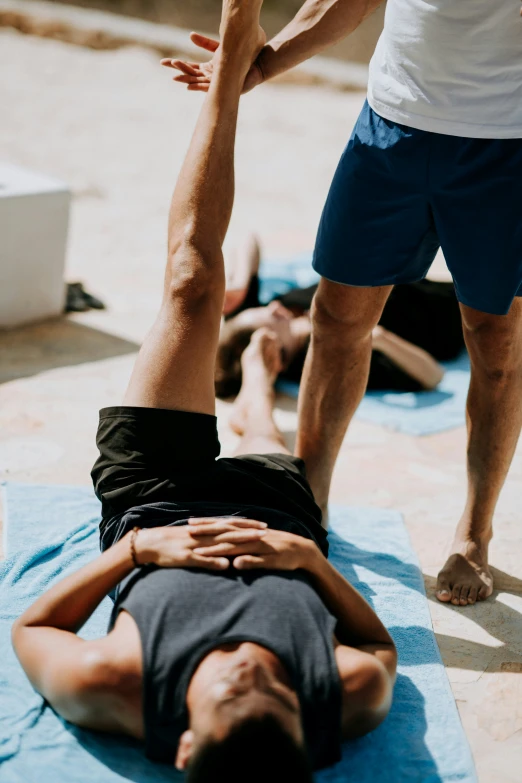 a person in blue shorts doing yoga on a mat with another person behind him