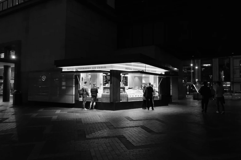 people are walking down a city sidewalk at night