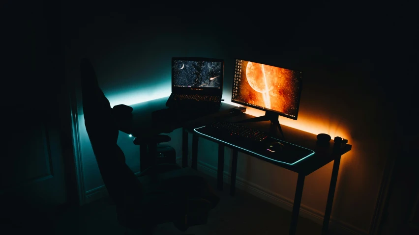 a dimly lit desk area with two computer monitors