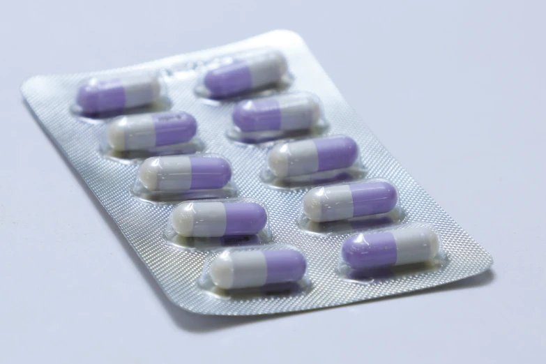 a pack of purple and white pills sitting on a pill tray