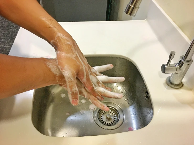 woman washing hands on the sink with soapy water