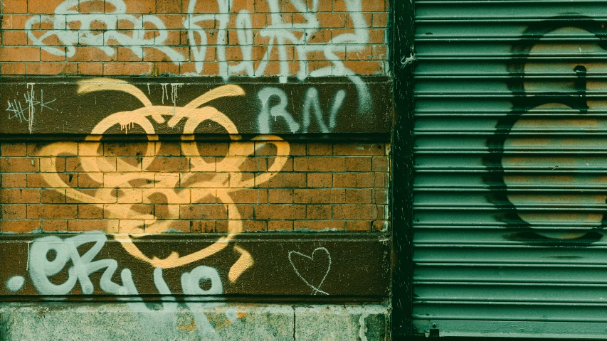 two large graffitti faces are on a brick wall