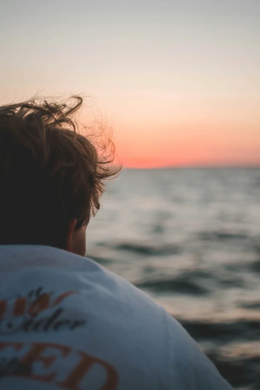 a man looking out at the water during a sunset