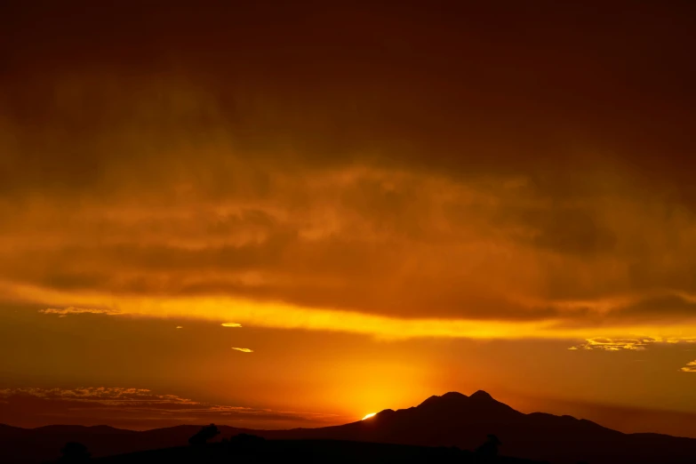 the sun is setting above the mountains with the clouds