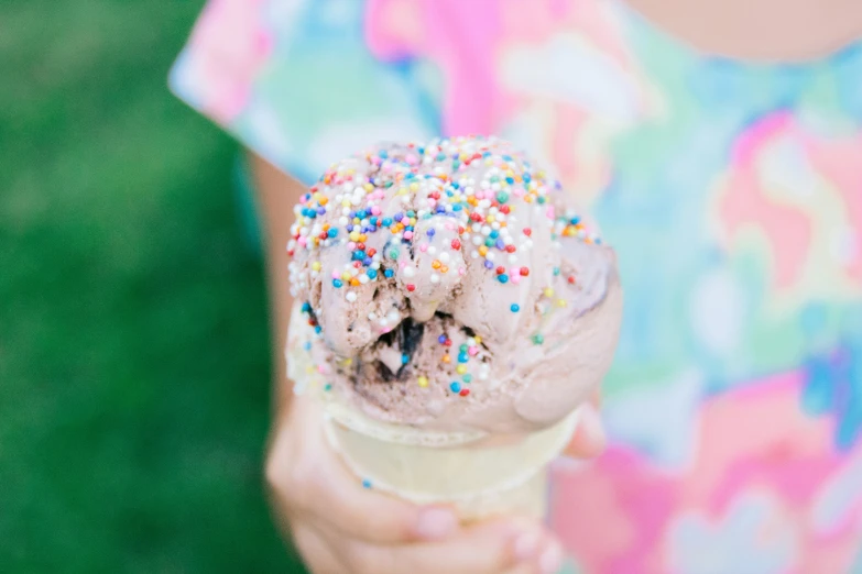 someone holding up an ice cream cone covered in sprinkles