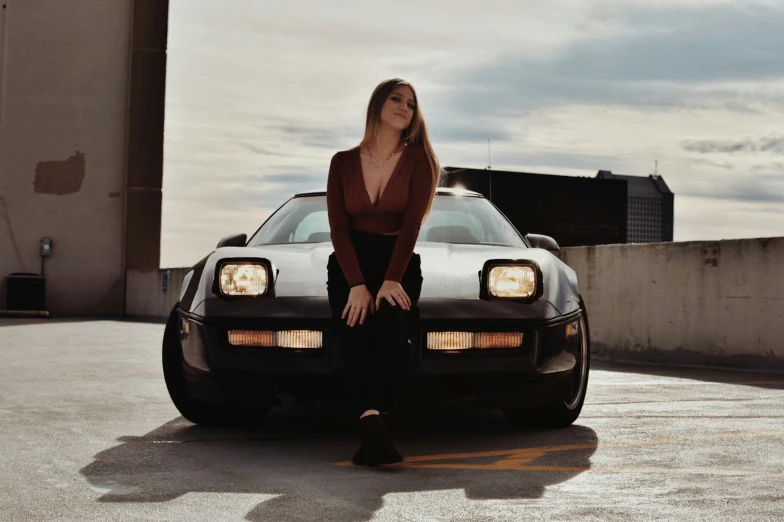 a woman in a red top is leaning on a car