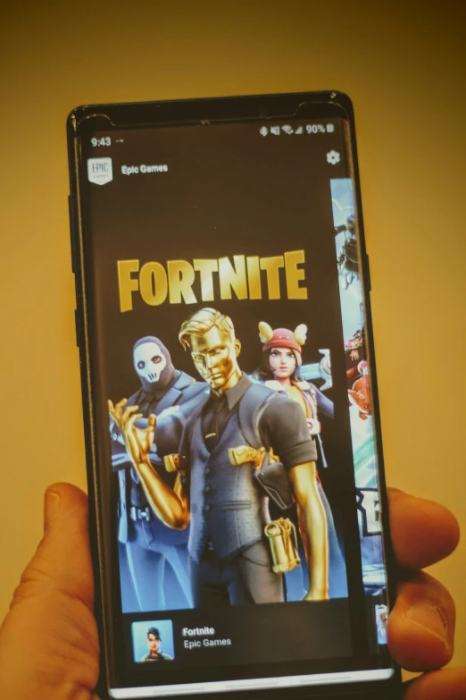 a person holds up their cell phone with the app fortnite on the back