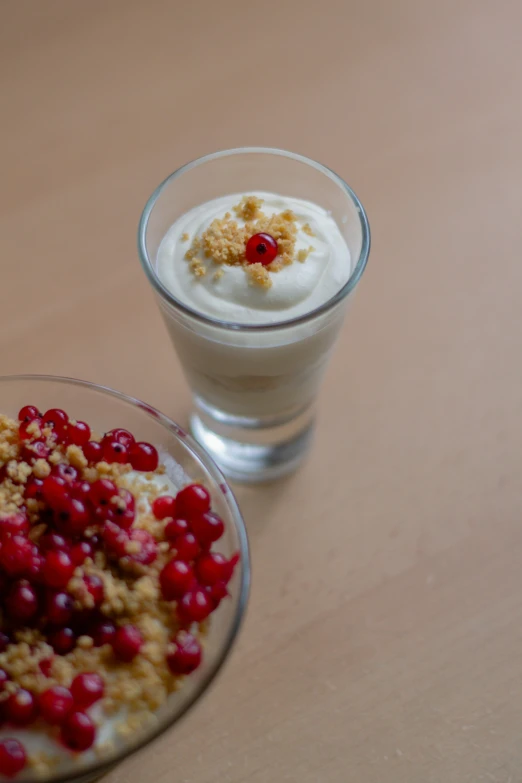 two desserts are served in a glass, one of which has white cream and cranberries on it