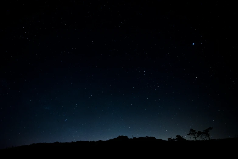 silhouette with stars in night sky over mountains