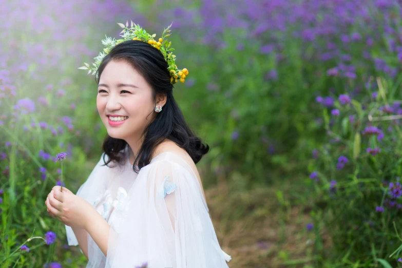 a smiling woman in a dress with flowers around her head