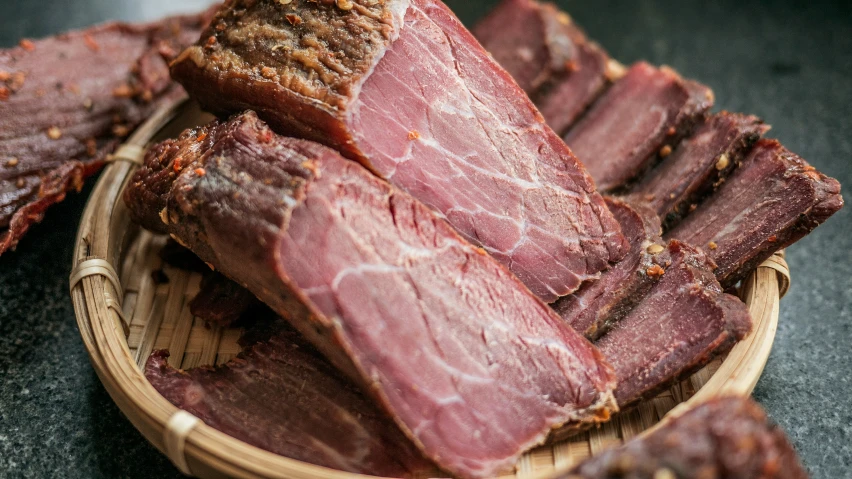 a wooden bowl filled with meat in a pile