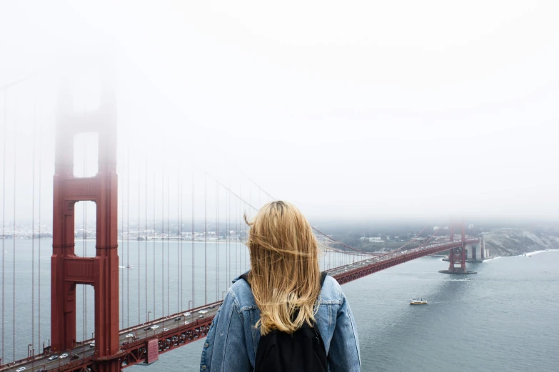 person standing in front of a bridge in a foggy weather