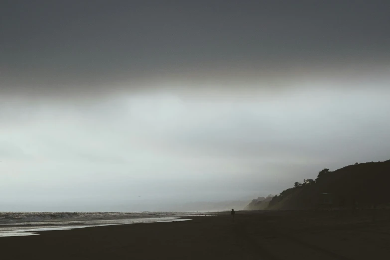 a person standing on a beach as the rain begins to fall