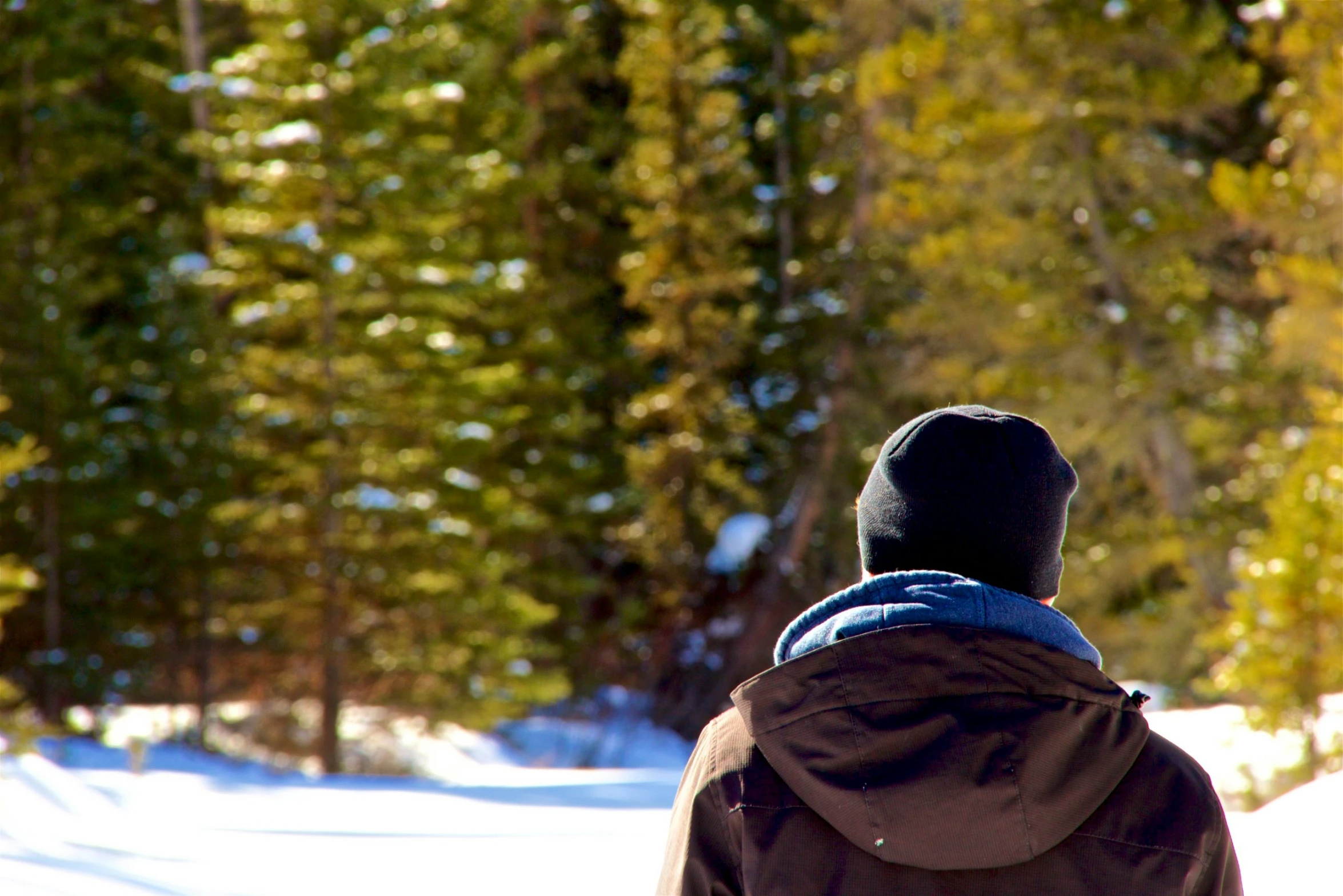 a man with a blue backpack and a coat in the snow