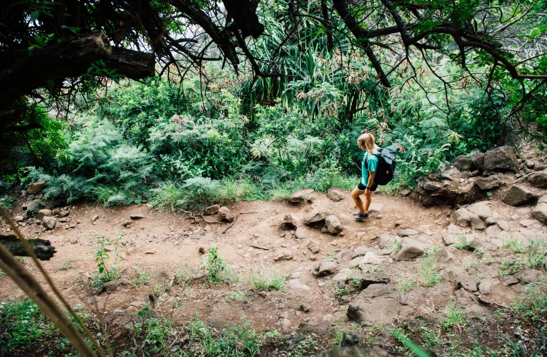 woman in blue backpack walking on dirt path