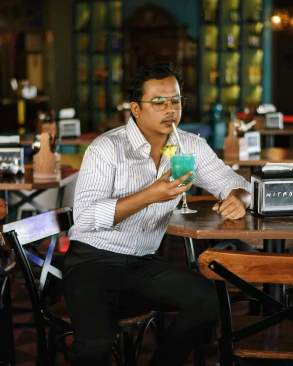 a man sitting at a table with a cocktail in his hand