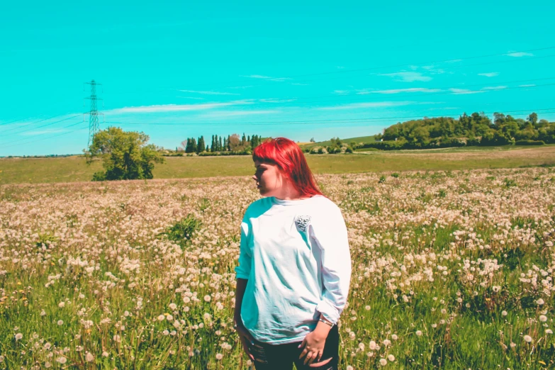 a young woman standing in a field, looking back