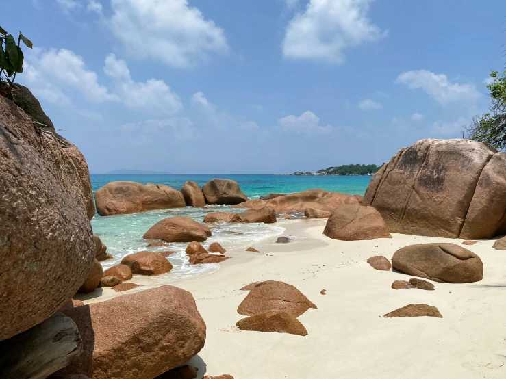 the beach is lined with large rocks and clear water