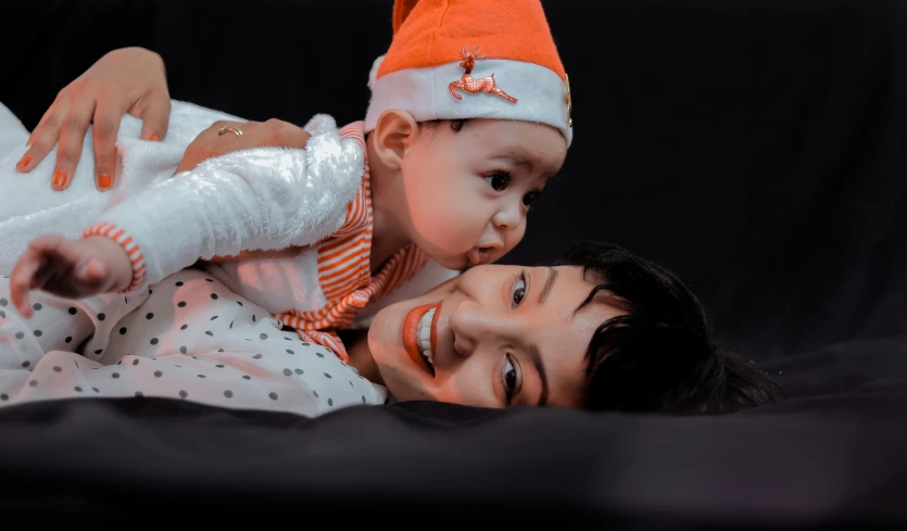 a woman in white shirt laying on a man's chest holding a child