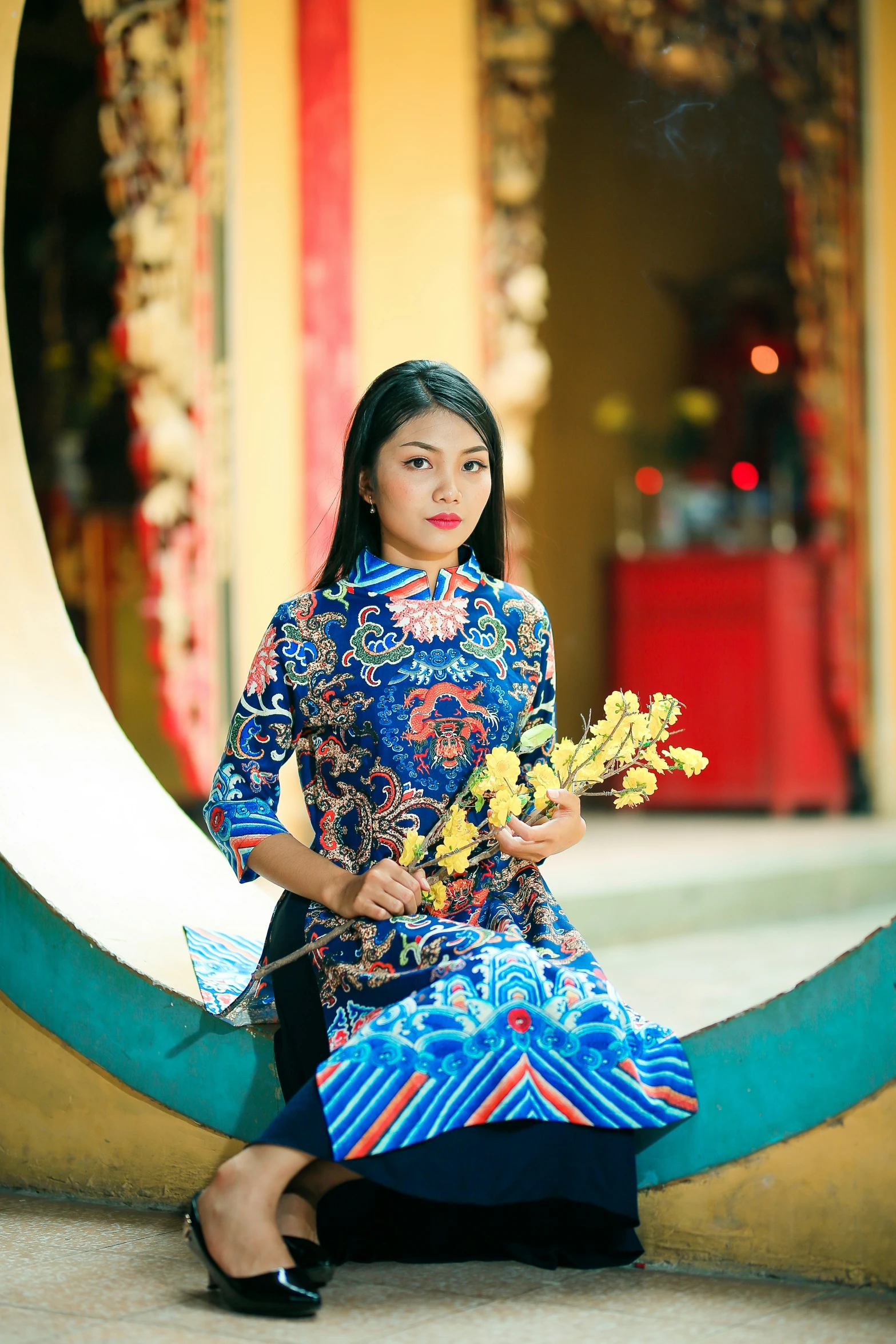 a girl in blue dress holding a bouquet sitting on the ground