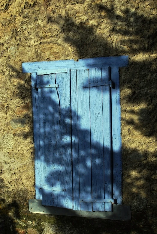 blue wooden door on the ground with a shadow cast