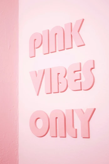 a pink sign on a wall with other pink objects hanging from the wall