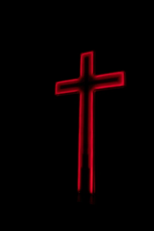 the cross is glowing red and shining in the darkness