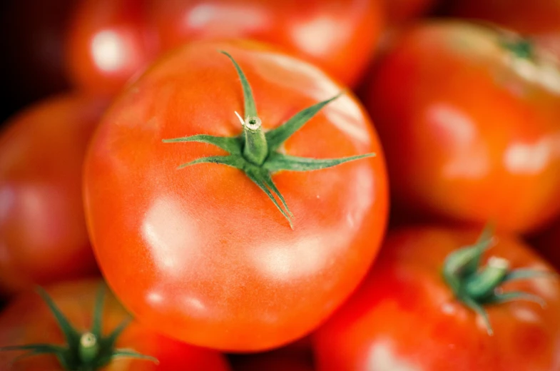 several ripe tomatoes stacked close together on a table