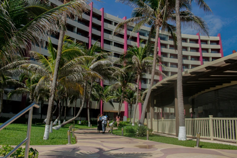 a large el with palm trees lining a walkway and people walking