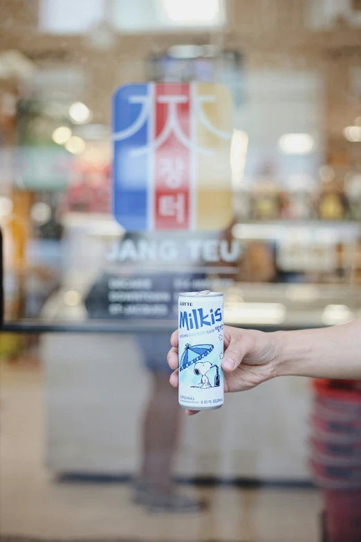 someone holding up a drink can with a white handle