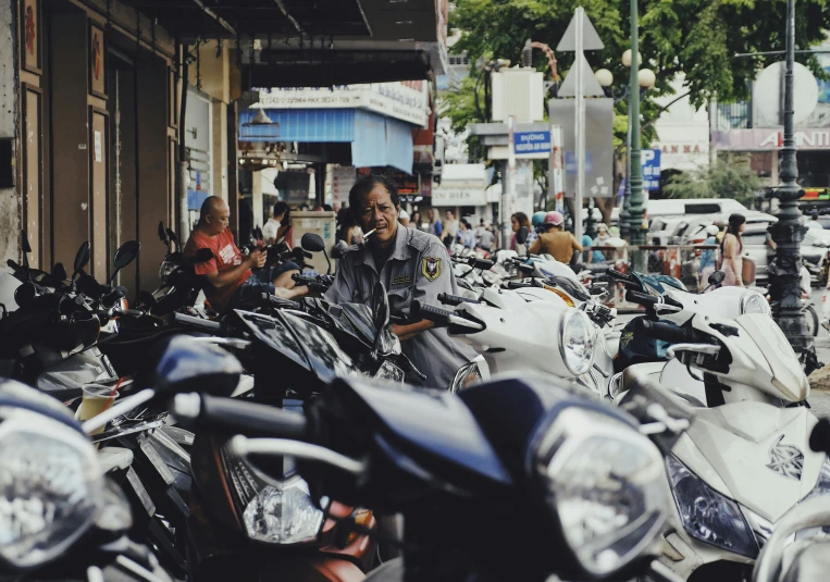 a man talking on a cell phone in a parking lot full of parked scooters