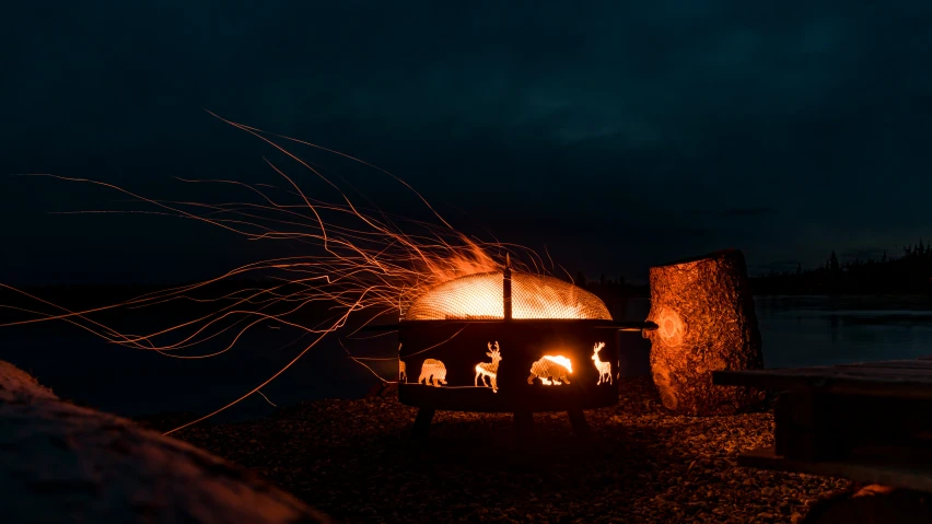 the fire is lit and is next to a lake