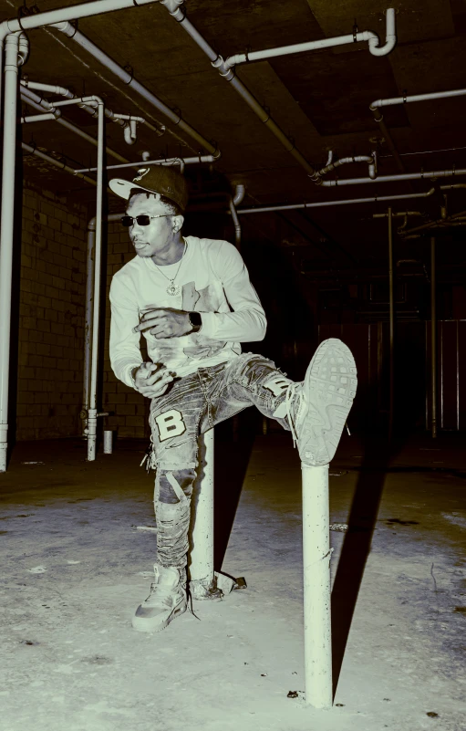 a skateboarder in jeans and white shirt sitting on a fence rail