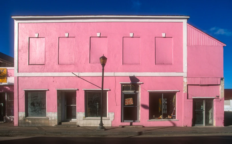 a pink building with no door is shown on a city street